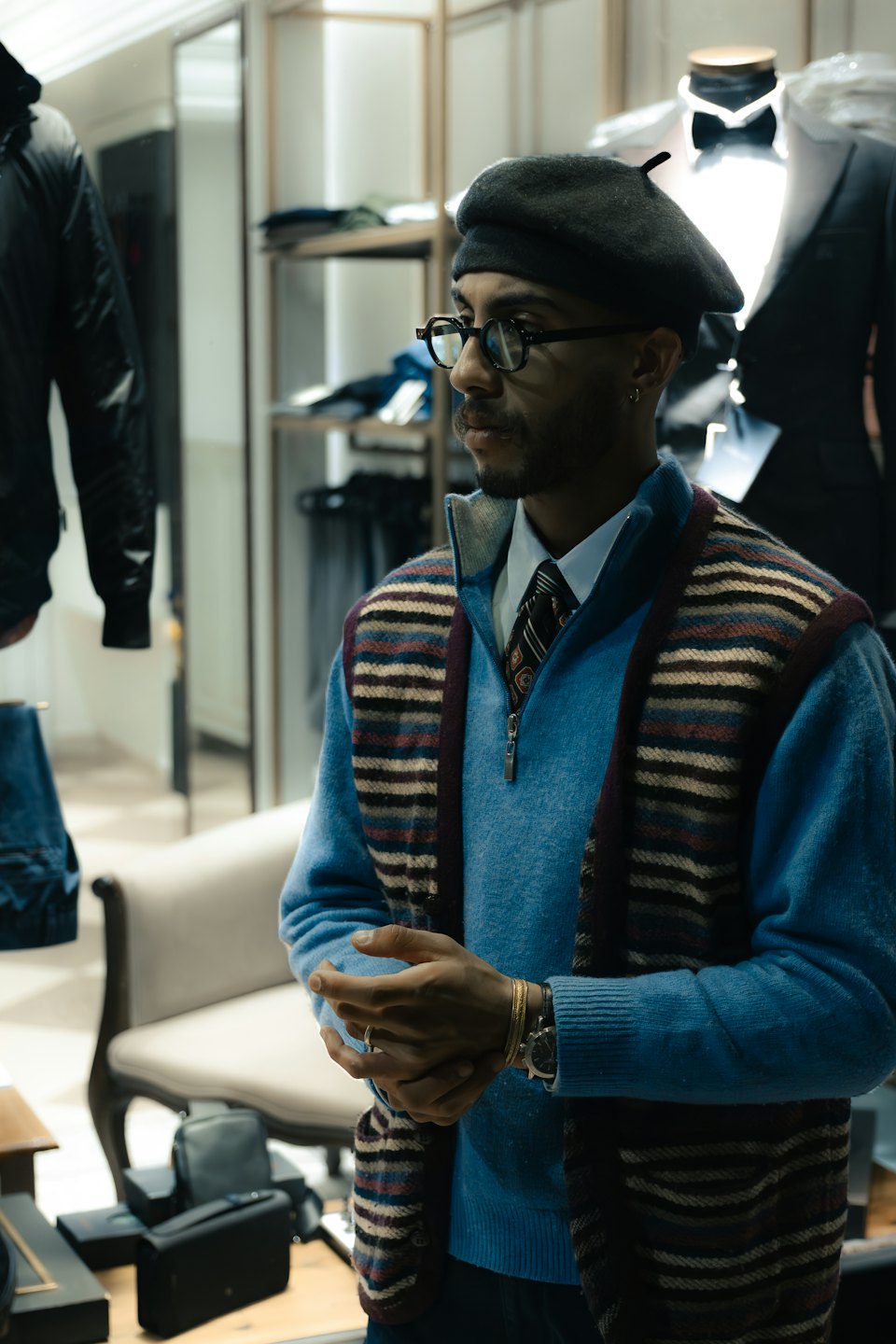 Man in a sweater and beret standing inside a clothing boutique.